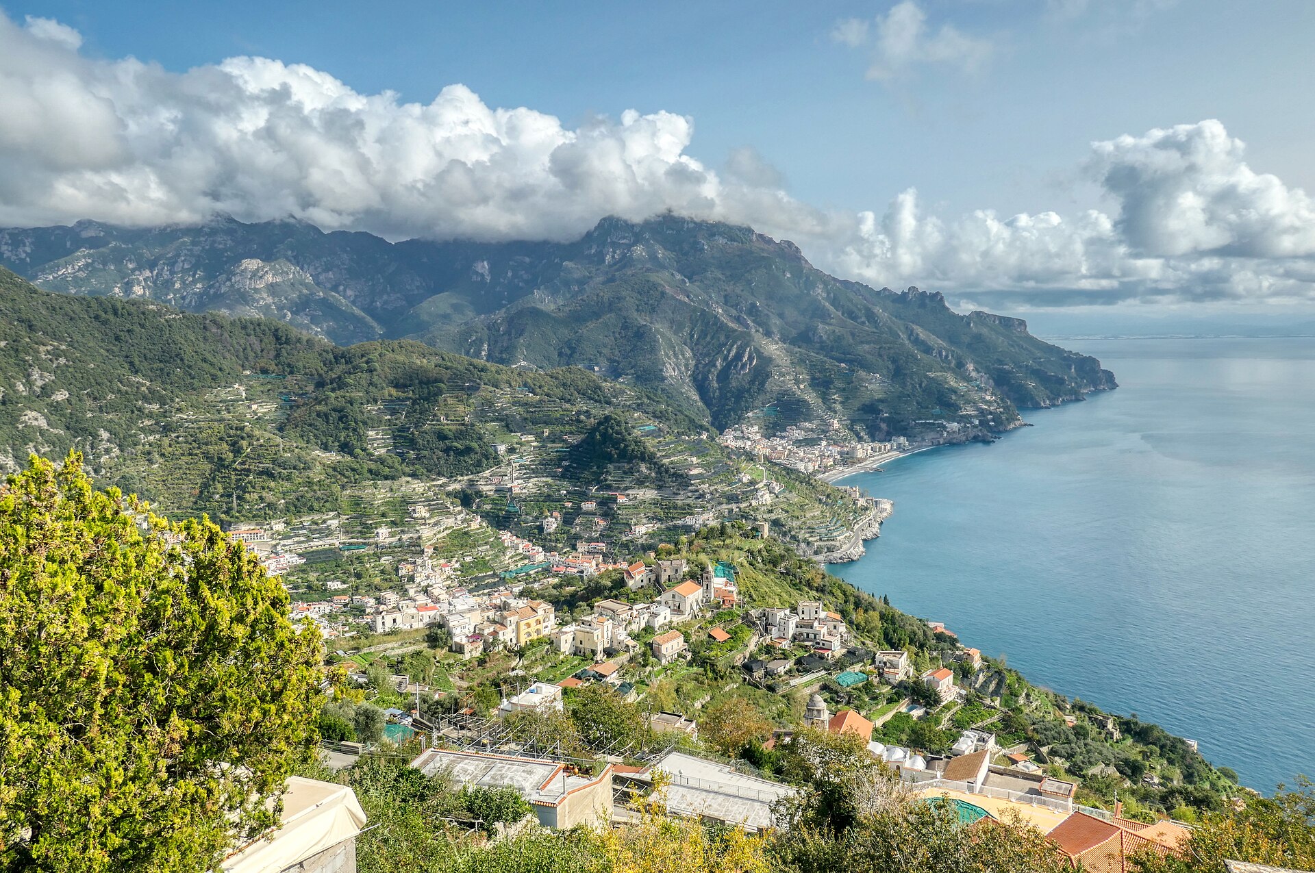 Veduta della Costiera amalfitana: terrazzamenti, borghi sul mare e monti con nubi, golfo di Salerno.